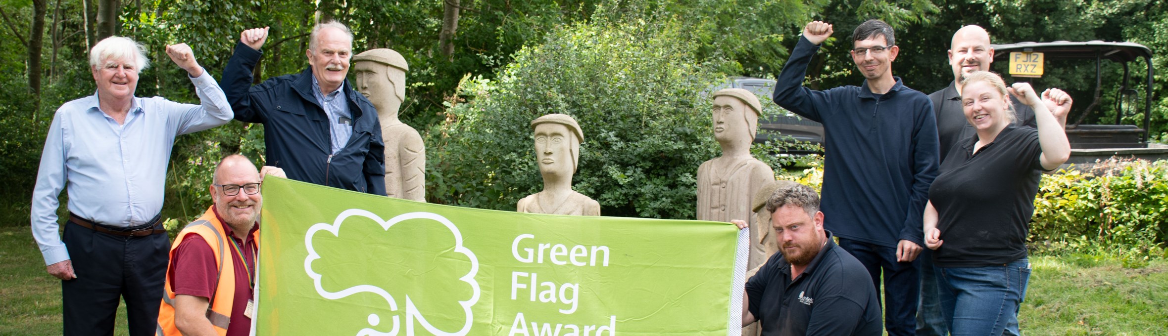 Members of the council showing off the Green flag at the Brierley Forest Park miners mural.