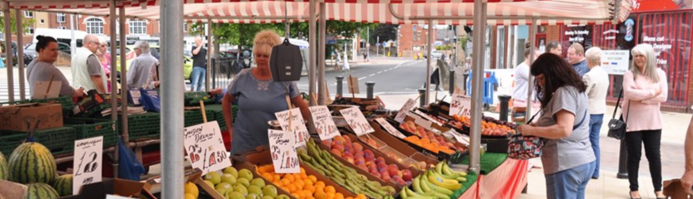 Fruit and veg market stall with people shopping in Hucknall