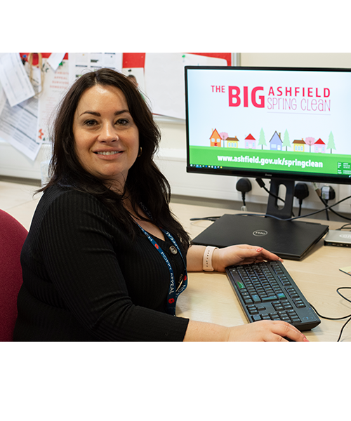 Woman sat in front of a computer monitor displaying logo for The Big Ashfield Spring Clean