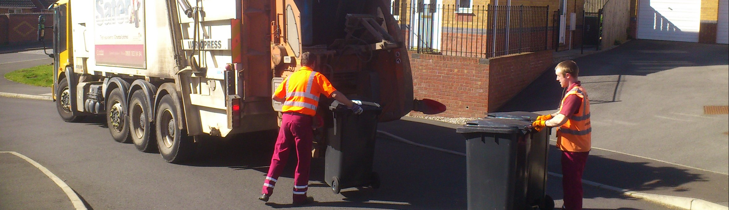 Refuge lorry collecting waste outside house with workers 