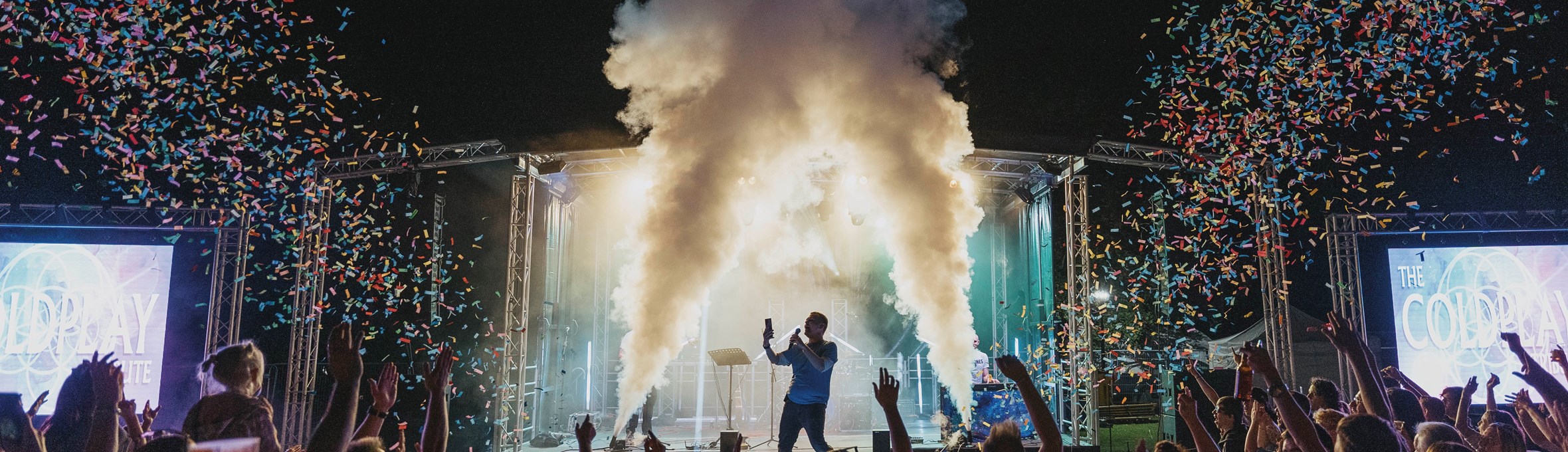 Headline act The Ultimate Coldplay Tribute performing on stage with a crowd of people and confetti
