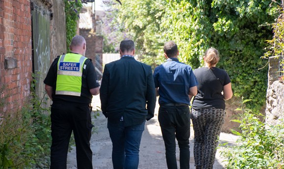 A Safer streets CPO walks down an alleyway with councillors 
