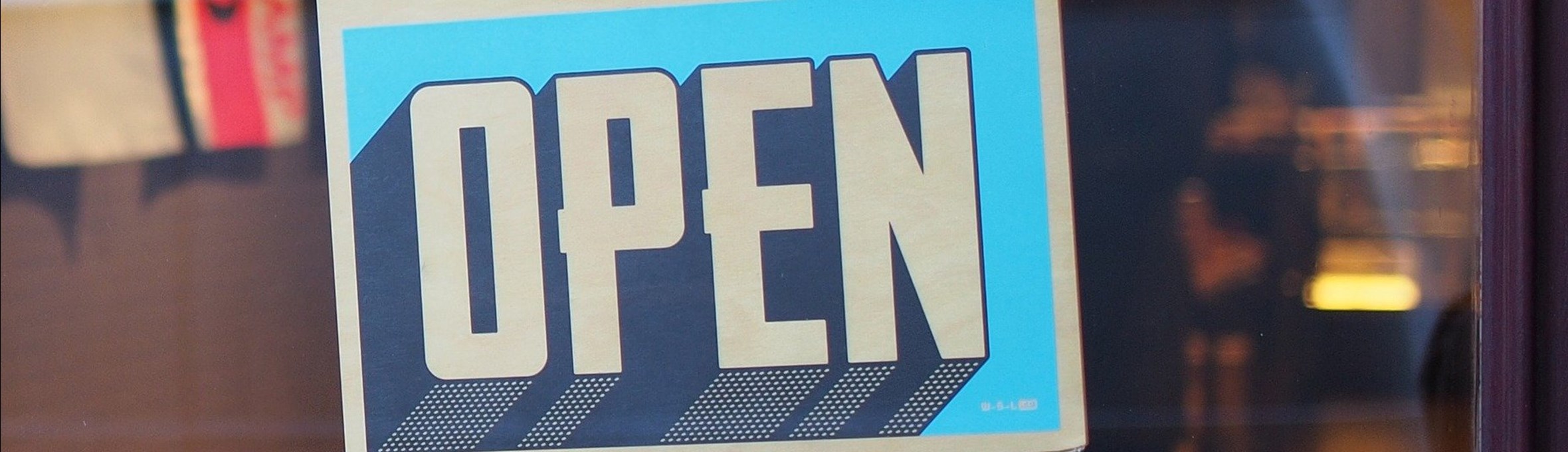a sign hangs in a window, the sign reads open