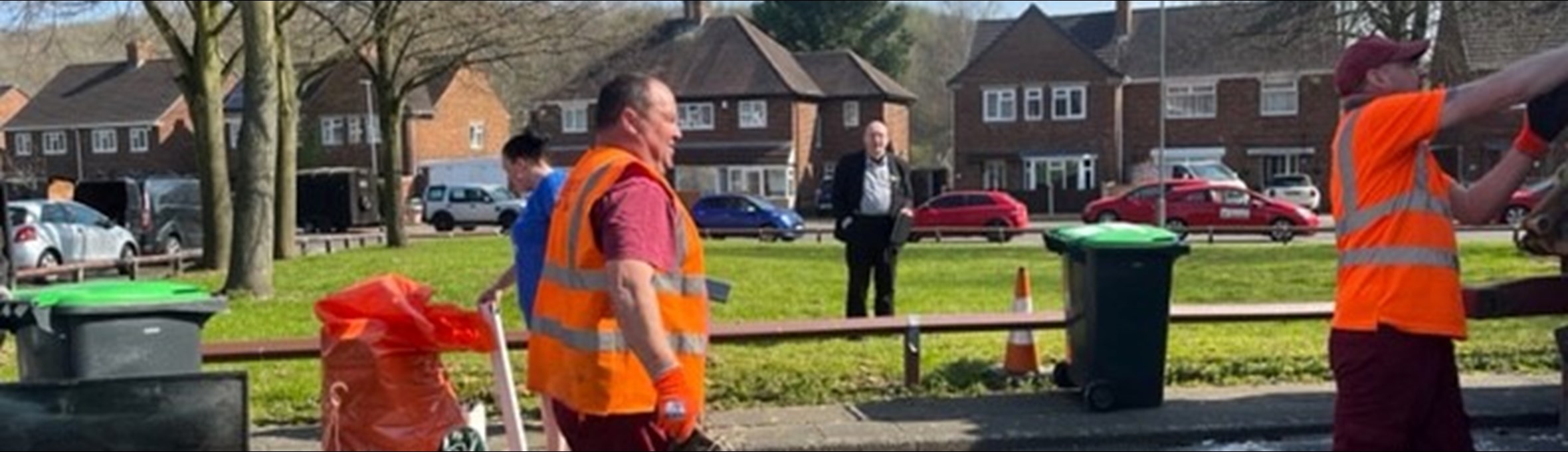 Two men in high vis vests throw rubbish into a dustbin lorry 