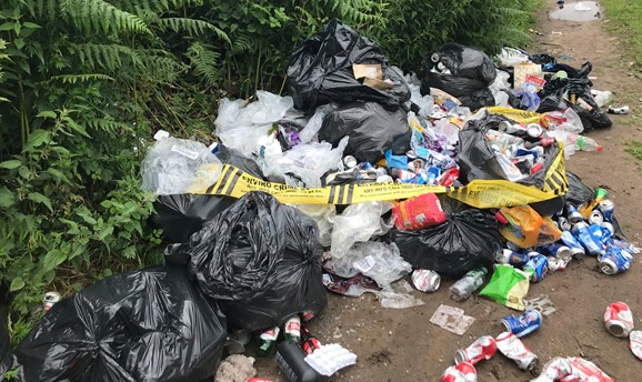 big pile of domestic waste in bags on a dirt path 