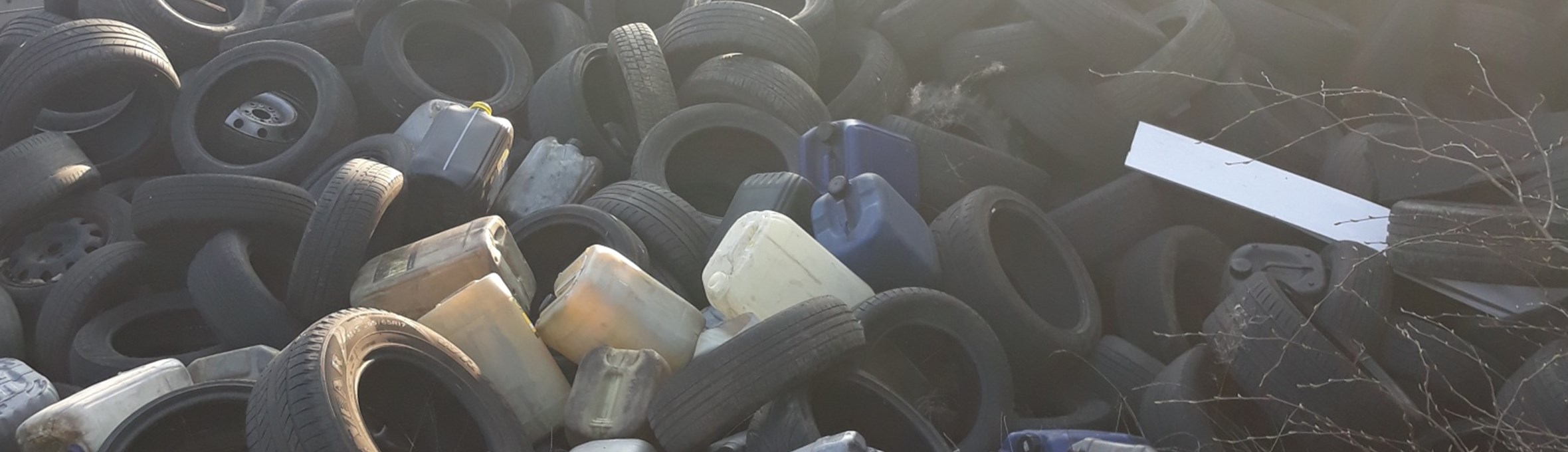 Example of fly tipping - tyres and plastic containers in a heap next to a building