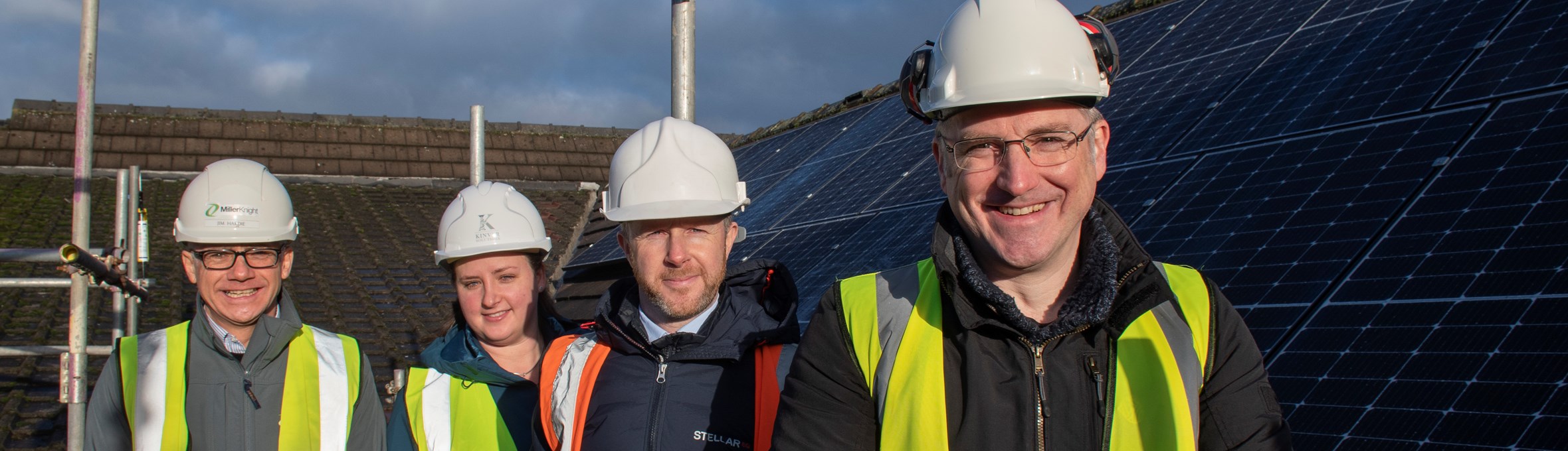 Cllr Relf smiling on a roof in front of solar panels 