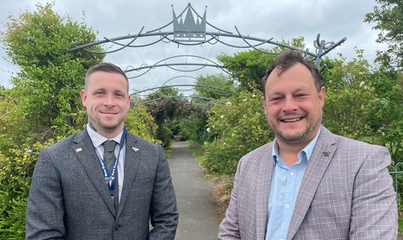 Cllr Dale Grounds and Cllr Jason Zadrozny stand in suits in front of a crown arch 